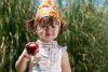 9168740-little-girl-eats-peach-in-the-park.jpg